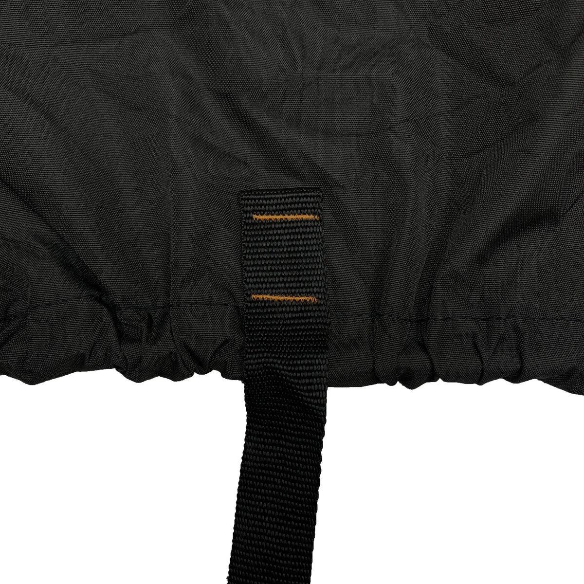 Close-up of strap and elastic hem on a black vehicle cover, designed to secure the cover tightly underneath the vehicle and prevent shifting, flapping, or wind lift during outdoor storage.