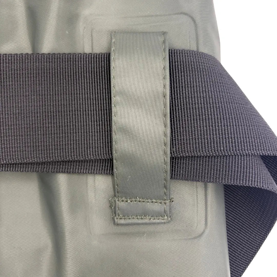 Close-up view of the heavy-duty fabric belt loop on the side of SavvyCraft green waterproof chest waders, securing a thick, dark gray woven wading belt.