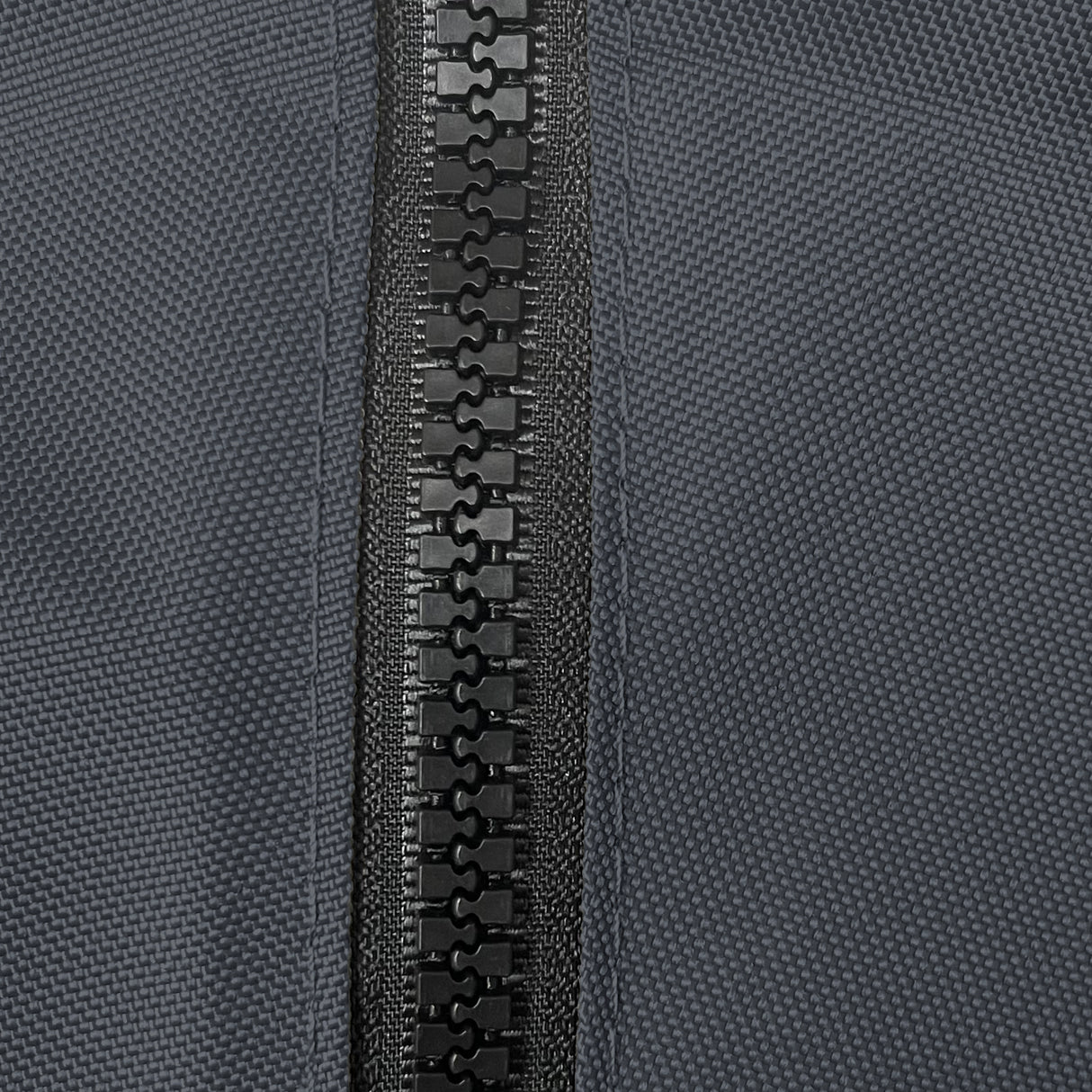 Close-up of heavy-duty black plastic zipper securely stitched on durable black woven polyester fabric, showcasing weather-resistant, marine-grade construction for sailboat jib bags, designed for long-lasting outdoor performance and protection