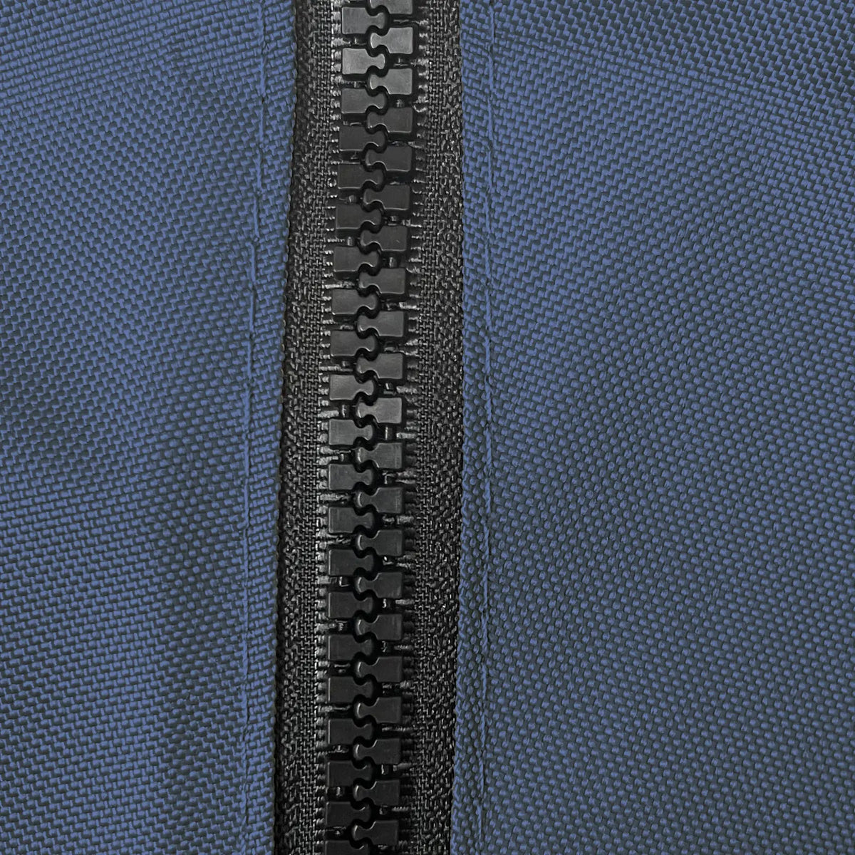 Close-up of heavy-duty black plastic zipper securely stitched on durable navy woven polyester fabric, showcasing weather-resistant, marine-grade construction for sailboat jib bags, designed for long-lasting outdoor performance and protection