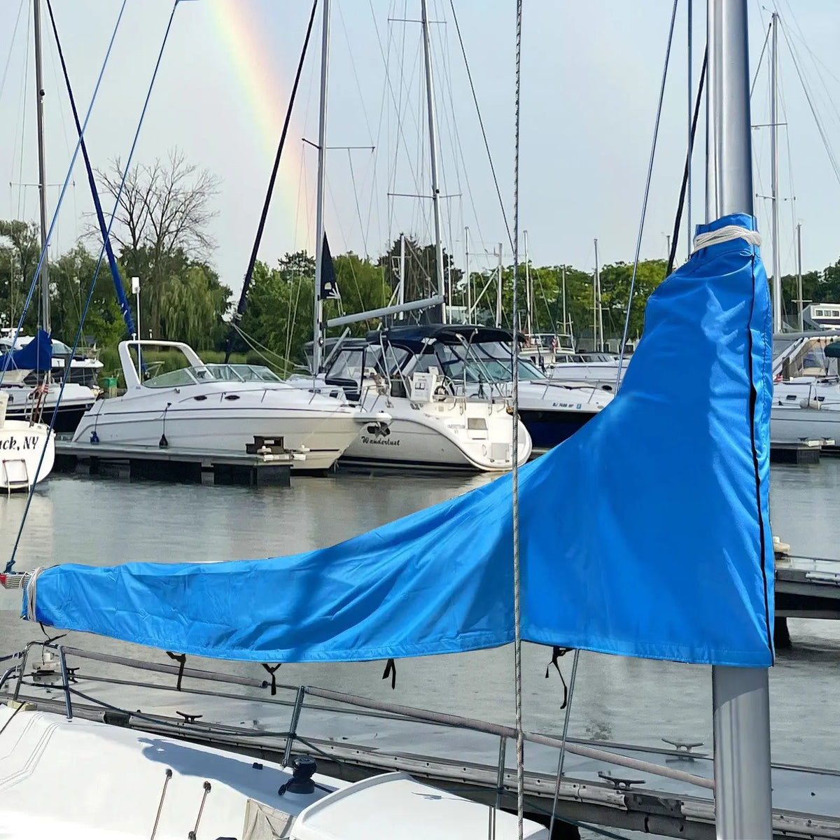 Blue waterproof sailboat boom cover installed on sailboat at marina