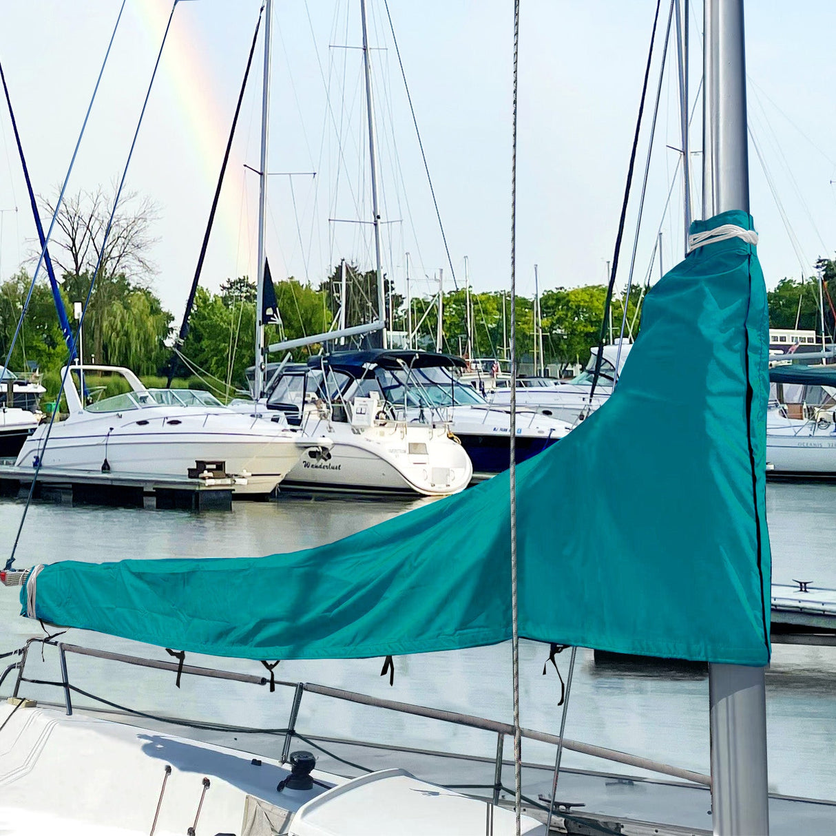 Teal waterproof sailboat boom cover installed on sailboat at marina