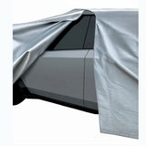 Tesla cybertruck partially covered with a silver car cover on a white background